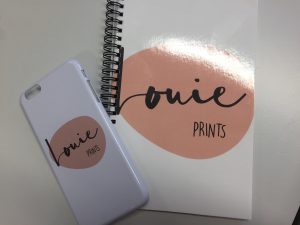 An image showing a notebook and phonecase with the Louie Prints logo