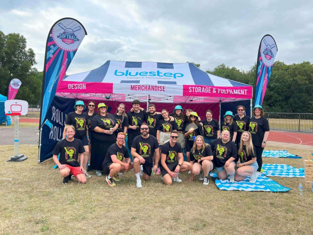 A group of the Bluestep team posing in front of a branded softball tent before the game